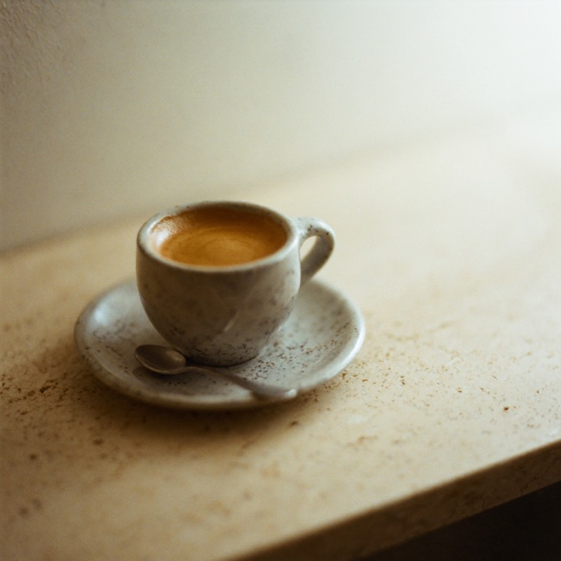 A single espresso with thick crema in a small speckled cup