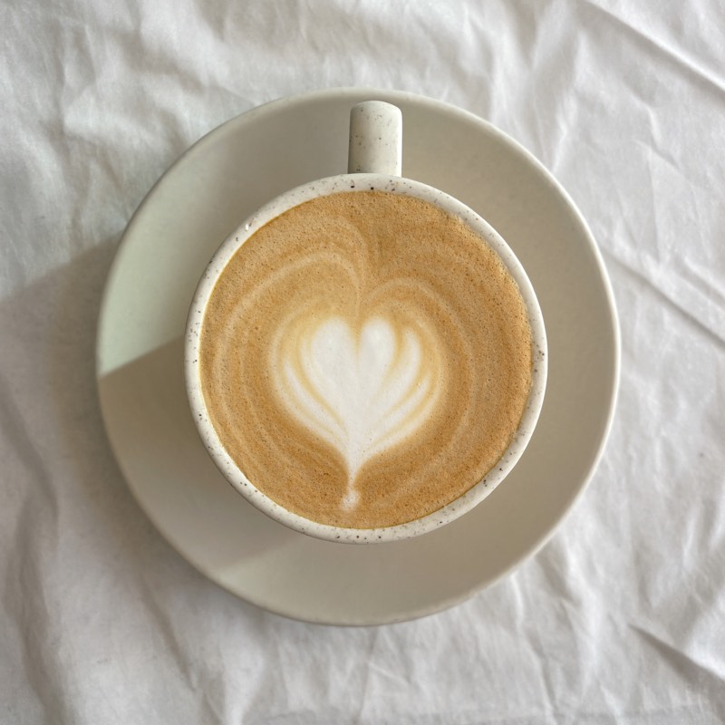 A flat white with tulip latte art in a speckled cream cup