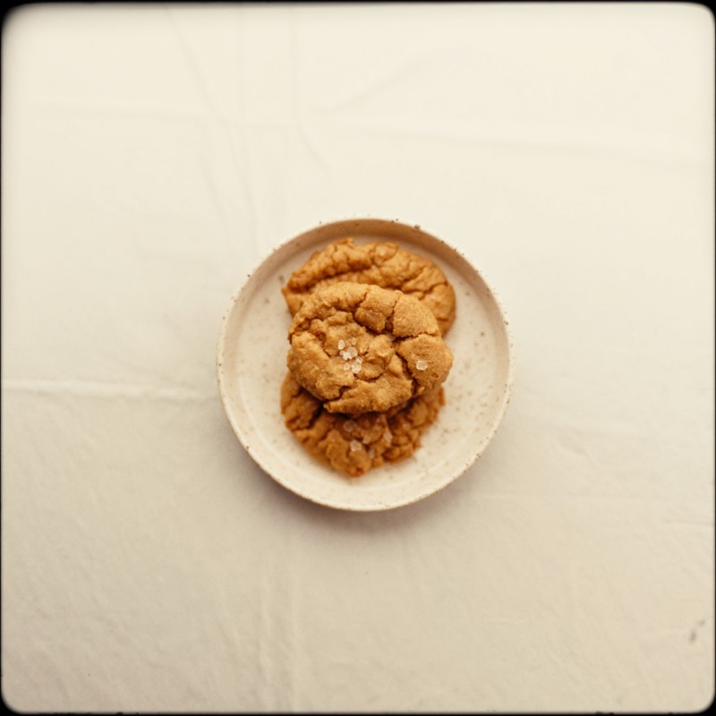 Two brown butter cookies with crackled tops and sea salt
